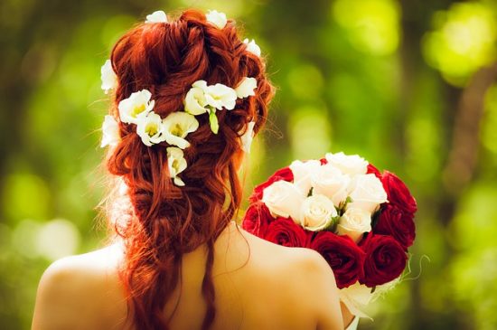 Lovely black woman putting white flowers in her hair and looking to the  right Stock Photo - Alamy